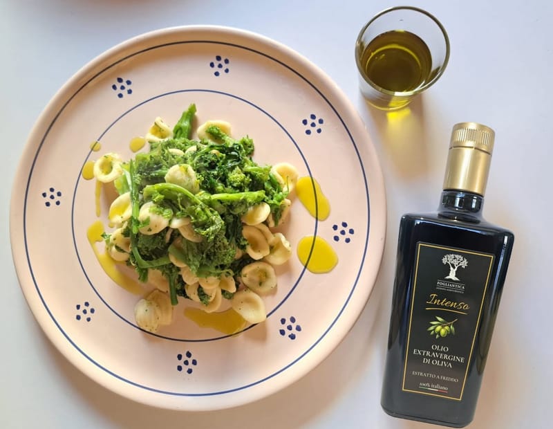 Orecchiette con cime di rapa neben einer Flasche Fogliantica Intenso und einem Glas frisch gepresstem Öl